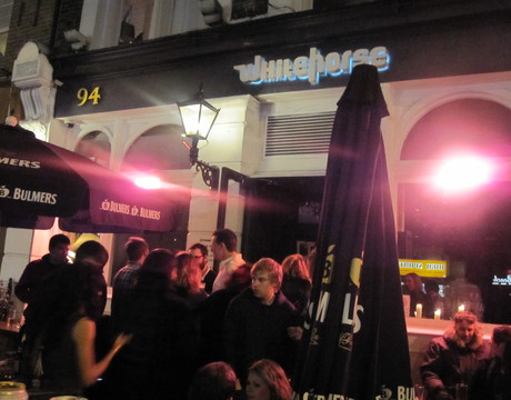 People gather outside the doors of White Horse in Brixton, London. 