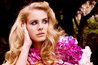 Lana Del Rey in a forest looking off in the distance.